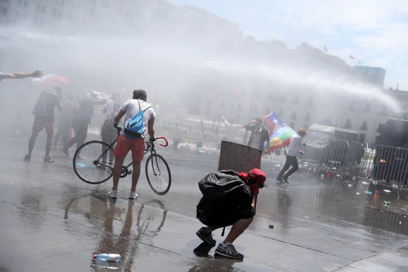 Manifestantes son dispersados por fuerzas de seguridad usando cañoes lanzaaguas durante una protesta contra el Gobierno en Santiago