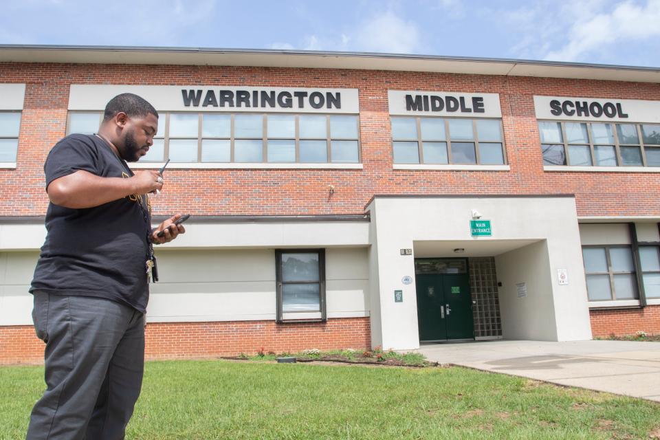 Assistant Principal Travis Griffin talks May 24 on a walkie-talkie outside Warrington Middle School. If the school does not receive a C grade from the Florida Department of Education this year, it will close after the 2022-2023 school year and reopen the following fall as a charter school.
