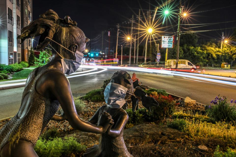 Surgical masks adorn the statues of cousins, Riley Lawrence and Claudia Wadlington, who were 4 and 5 years old, respectively, in July 2008 when they were hit and killed by a car speeding away from Louisville police.The statues were donated by James Weiter, owner of Luv-It Landscaping.  He and his wife add small touches, like Santa hats, to the statues depending on the season.  