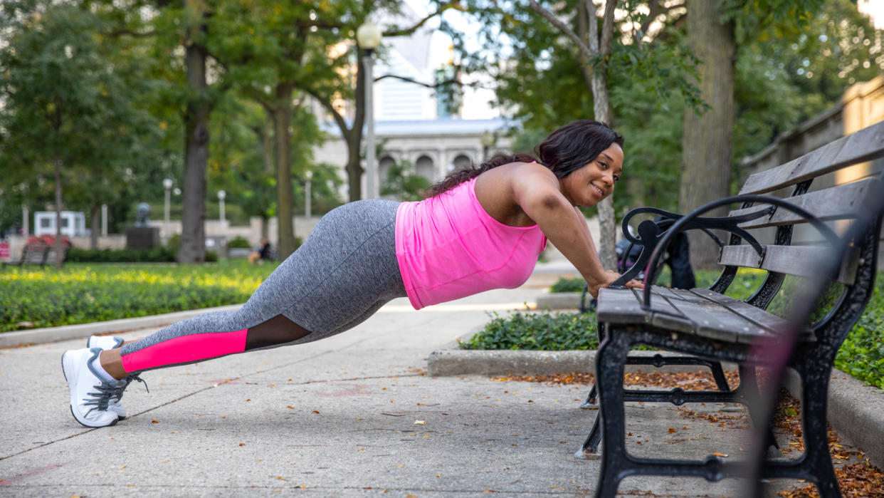  A woman performing a push-up on a park bench 