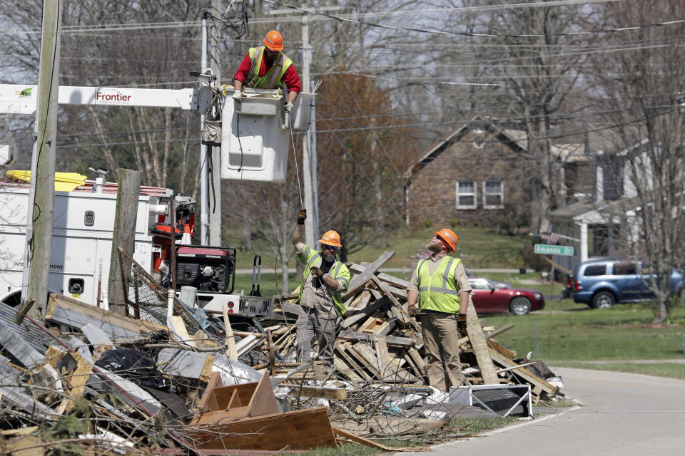 In this March 26, 2020, photo, utility workers repair a power line in a residential neighborhood in Cookeville, Tenn. People still reeling from the deadly twisters that hit the state on March 3 now have to confront life in the age of coronavirus. (AP Photo/Mark Humphrey)