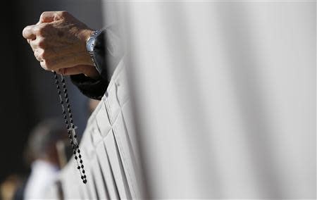 A faithful holds a rosary before the arrival of Pope Francis to lead the Easter mass in Saint Peter's Square at the Vatican April 20, 2014. REUTERS/Tony Gentile