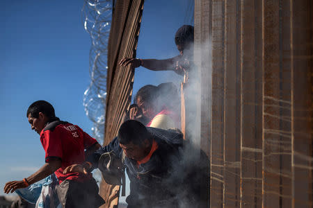 Migrants, part of a caravan of thousands from Central America trying to reach the United States, return to Mexico after being hit by tear gas by U.S. Customs and Border Protection (CBP) after attempting to illegally cross the border wall into the United States in Tijuana, Mexico November 25, 2018. REUTERS/Adrees Latif