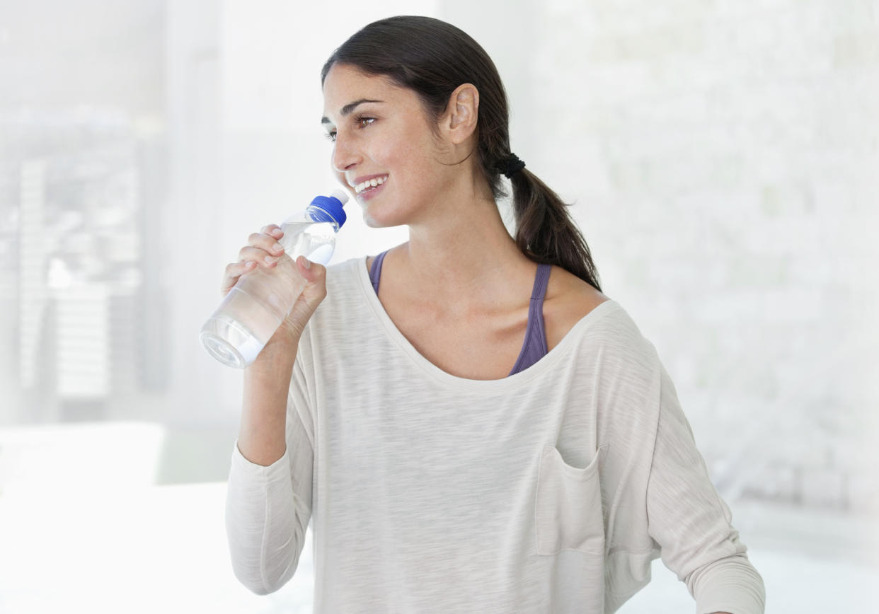 Smiling woman drinking from water bottle