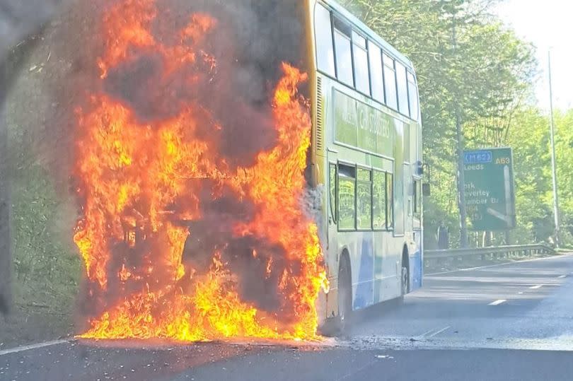 Photograph of a Stagecoach bus on fire on the A63. The rear end of the Stagecoach double-decker bus is consumed with orange flames. Thick black smoke is floating upwards.