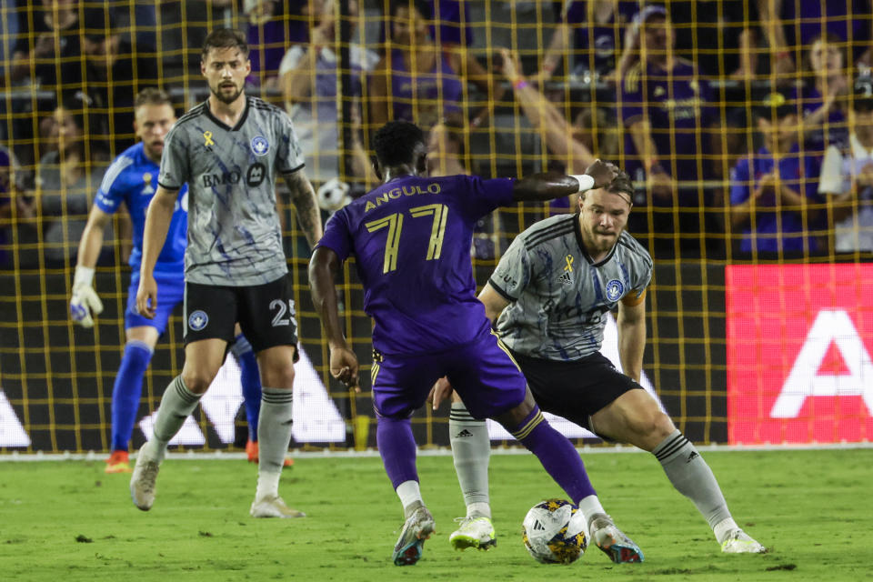Orlando City forward Ivan Angulo , center, brings ball downfield as CF Montreal midfielder Samuel Piette, right, defends against him during the first half of an MLS soccer match, Saturday, Sept. 30, 2023, in Orlando, Fla. (AP Photo/Kevin Kolczynski)