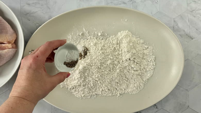 hand adding seasonings to salt