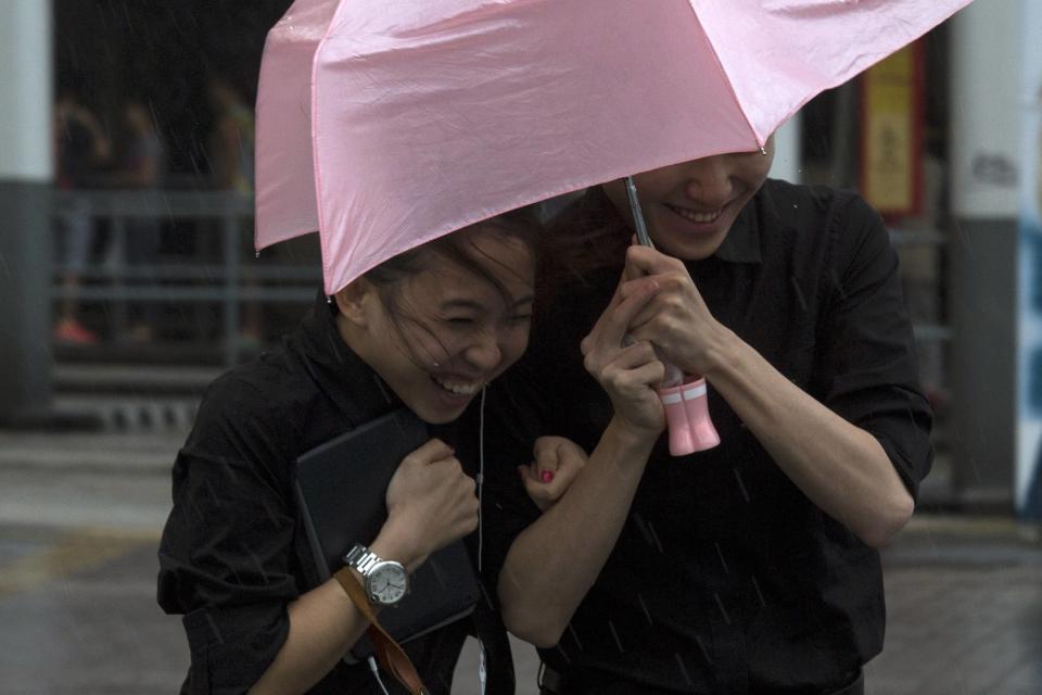 People brave gusty winds outside a shopping mall during Typhoon Usagi in Hong Kong