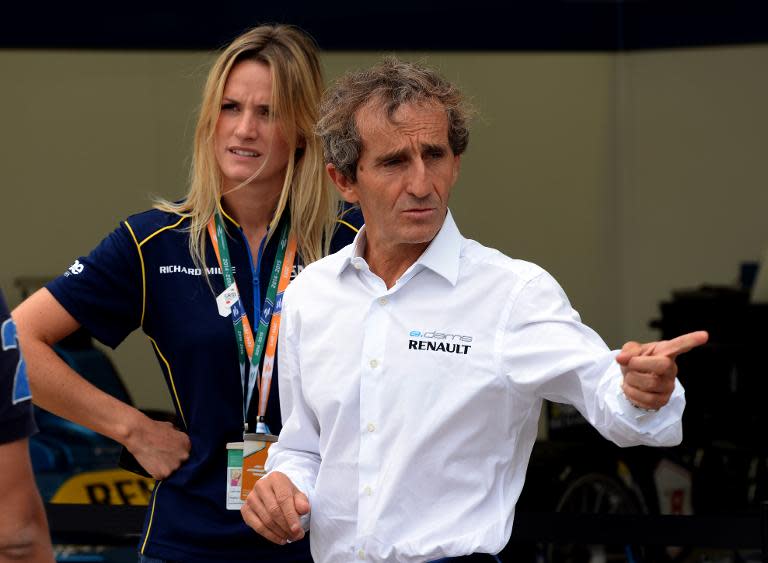Four-time Formula One world champion Alain Prost chats with an official at his e.dams-Renault team tent at the new Formula E venue in Beijing, on September 12, 2014