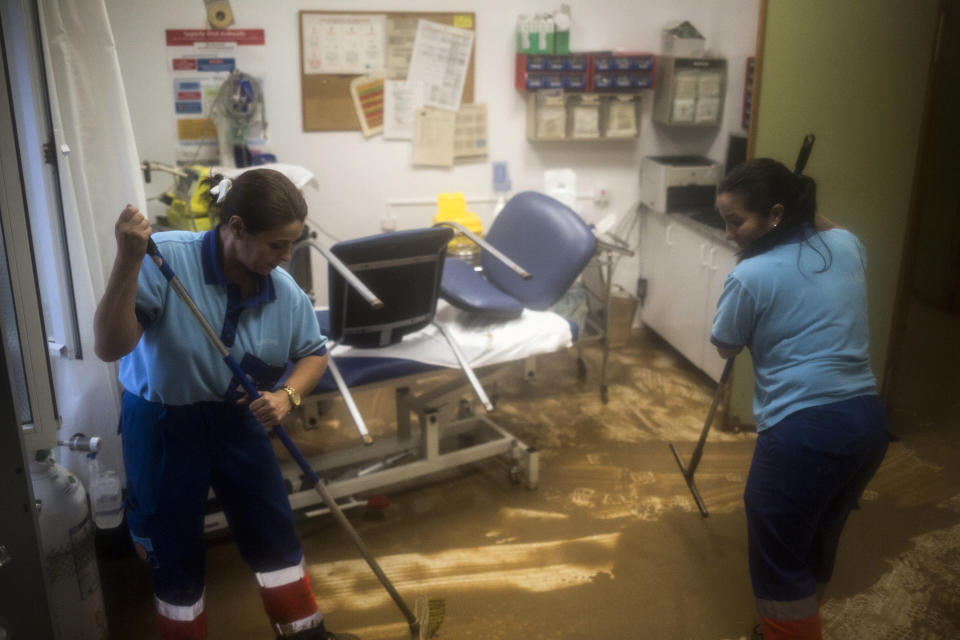 Medical staff clean the local emergency clinic in the village of Campillos, Spain, where heavy rain and floods have caused severe damage and the death of a firefighter according to Spanish authorities, on Sunday, Oct. 21 2018. Emergency services for the southern region of Andalusia say that the firefighter went missing when his truck overturned on a flooded road during heavy rains that fell through the night, and his body was found after a search Sunday morning. (AP Photo/Javier Fergo)