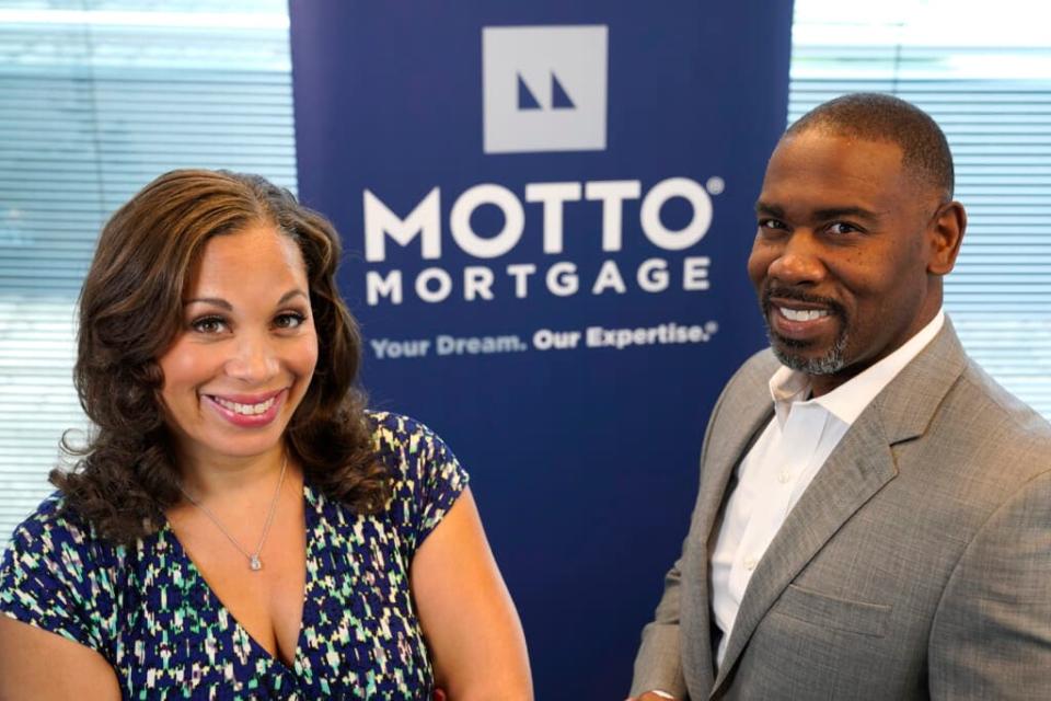 The husband and wife team of Kelly Jackson, right, and Davina Arceneaux stand for a portrait at their Motto Mortgage office Thursday, July 28, 2022, in Oakbrook Terrace, Ill. (AP Photo/Charles Rex Arbogast)