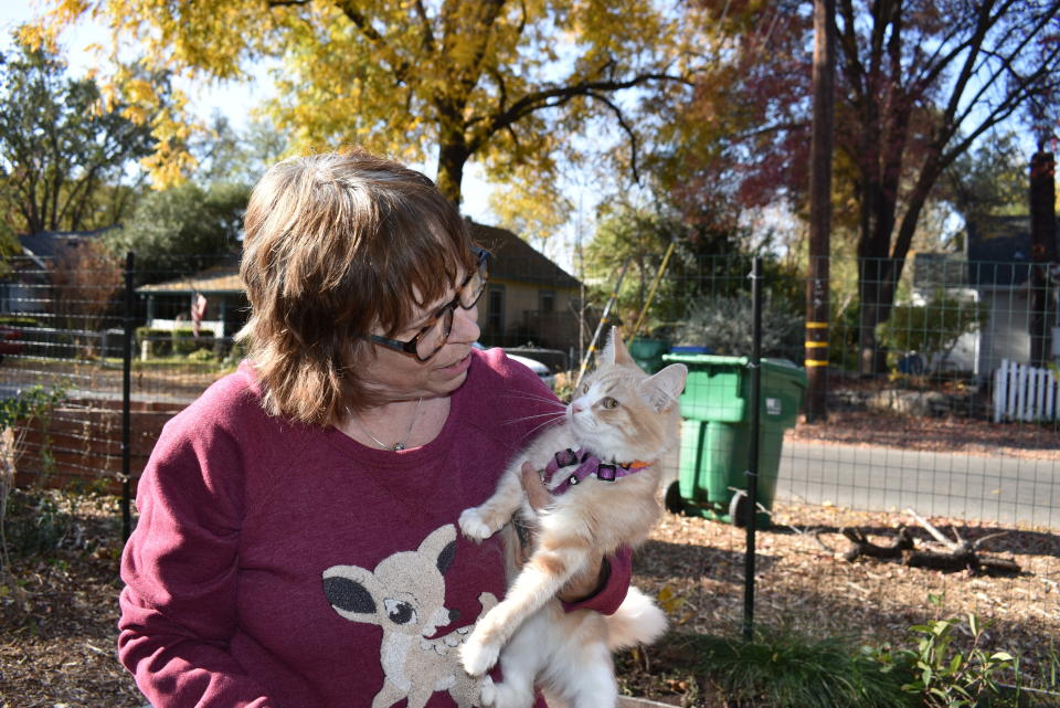 In this Friday, Nov. 22, 2019, photo, Elizabeth Watling holds her cat Tampopo as she talks about her health concerns over being exposed to wildfire smoke at her home in Chico, Calif. Watling says the fire that obliterated the nearby town of Paradise filled Chico's air with smoke for two weeks and left a coating of ash on the ground. (AP Photo/Matthew Brown)