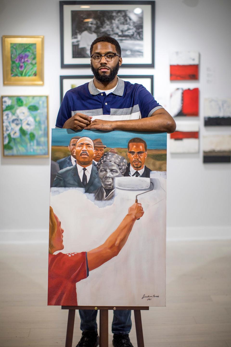 Jonathan Harris stands next to his painting titled, “Critical Race Theory” at Irwin House Gallery in Detroit on Thursday, Dec. 2, 2021. Harris recently had an art show titled TRIPTYCH: Stronger Together introducing artists Crystal Starks-Webb and Terrell Anglin at Irwin House Gallery.