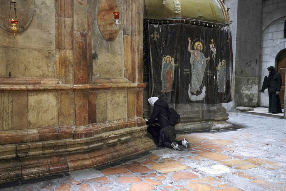 A woman pray at the Church of the Holy Sepulchre, where many Christians believe Jesus was crucified, buried and rose from the dead, in the Old City of Jerusalem, Thursday, March 17, 2022. The three Christian communities that have uneasily shared their holiest site for centuries are embarking on a project to restore the ancient stone floor of the Jerusalem basilica. The project includes an excavation that could shed light on the rich history of the Church of the Holy Sepulchre in the Old City. (AP Photo/Mahmoud Illean)