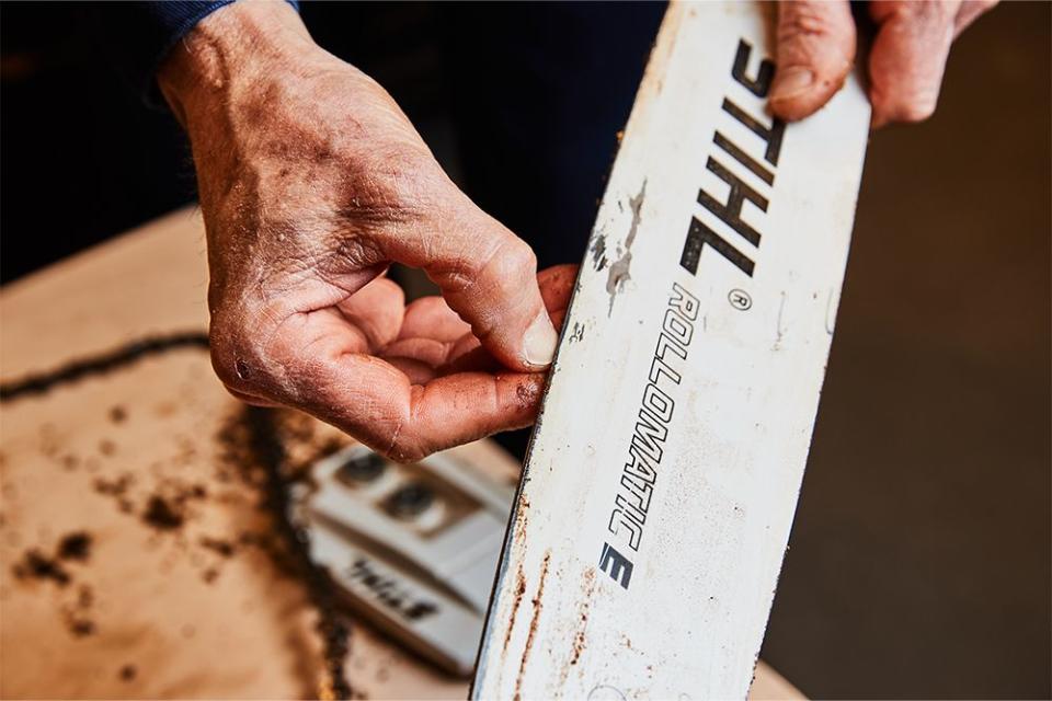 a person running their finger nail along the groove of a chainsaw