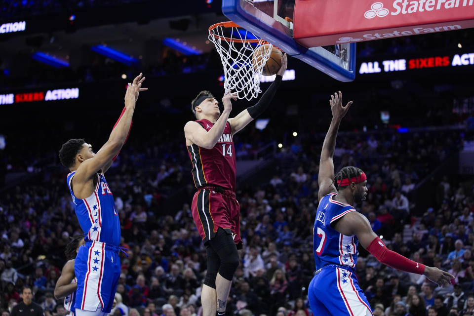 Miami Heat's Tyler Herro (14) goes up for a shot against Philadelphia 76ers' KJ Martin and Buddy Hield during the first half of an NBA basketball game, Wednesday, Feb. 14, 2024, in Philadelphia. (AP Photo/Matt Rourke)