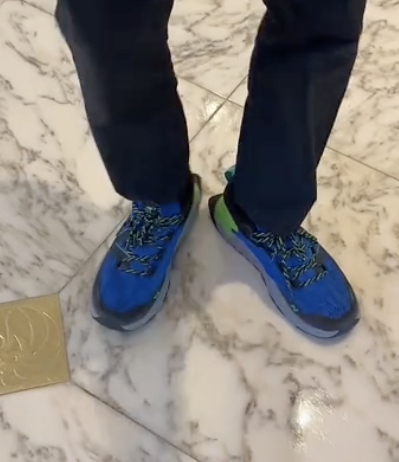 A close-up of Seth's shoes on marble flooring with sneakers and dark pants; no faces visible