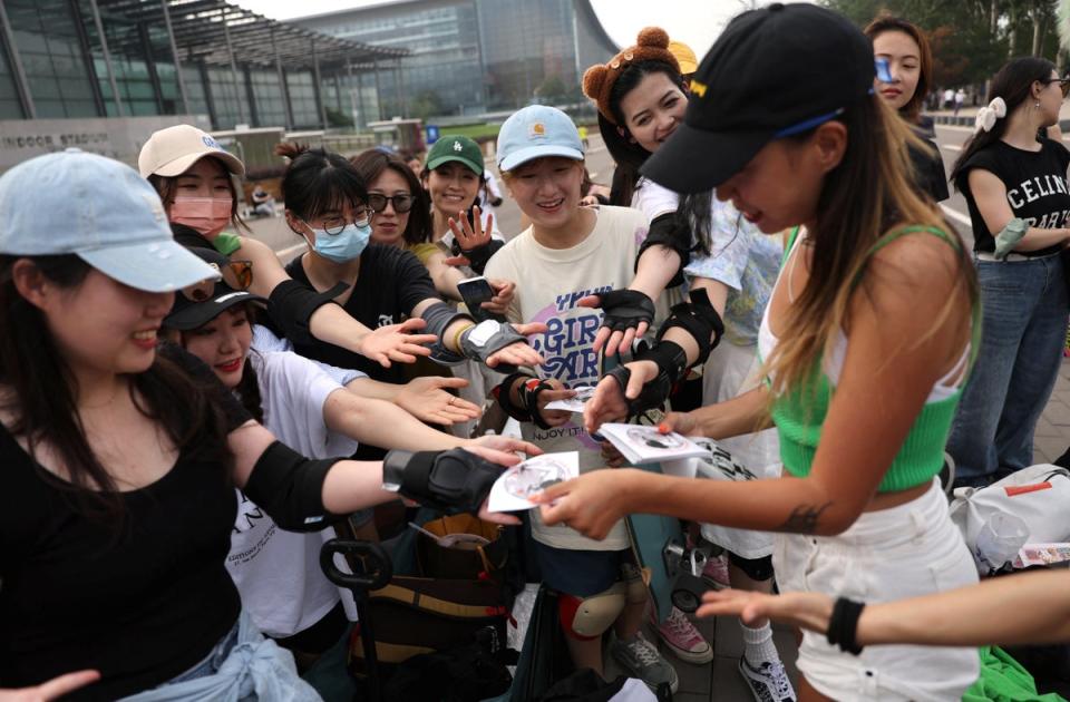 The founder of Beijing Girls Surfskating Community, distributes stickers with the community's logo to the members, during a free weekly training session in Beijing (Reuters)