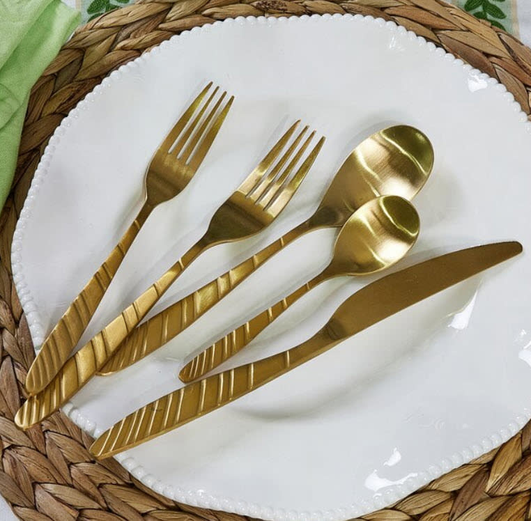 two forks, two spoons and 1 knife gold flatware on top of white plate