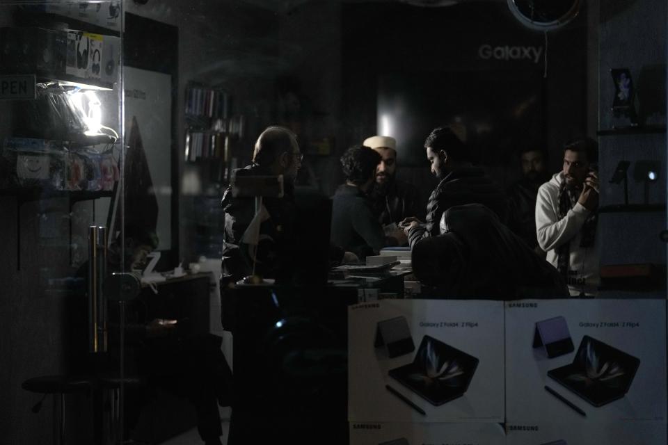 A shopkeeper use a battery light at his mobile selling shop to deal customers during a national-wide power breakdown, in Islamabad, Pakistan, Monday, Jan. 23, 2023. Much of Pakistan was left without power Monday as an energy-saving measure by the government backfired. The outage spread panic and raised questions about the cash-strapped government's handling of the country's economic crisis. (AP Photo/Anjum Naveed)