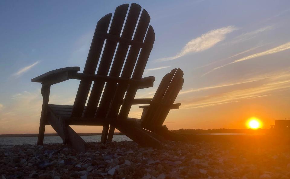 The sun sets over Barnstable Harbor June 6, offering a pair of Adirondack chairs a front-row seat. Steve Heaslip/Cape Cod Times
