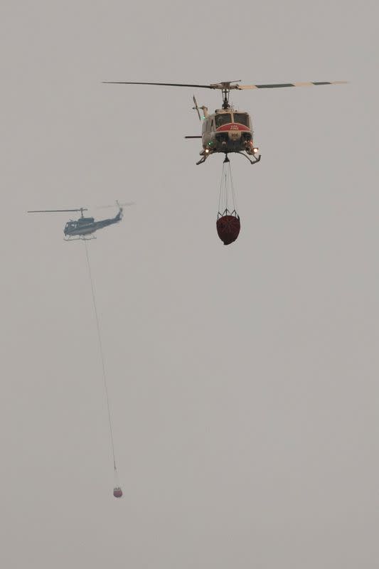 Helicopters and crew carry water to extinguish section of LNU Lightning Complex Fire near Middletown, California