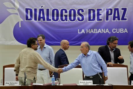 Colombia's lead government negotiator Humberto de la Calle (R) and Colombia's FARC lead negotiator Ivan Marquez shake hands after signing the protocol and timetable for the disarmament of the FARC in Havana, Cuba, August 5, 2016. REUTERS/Enrique de la Osa