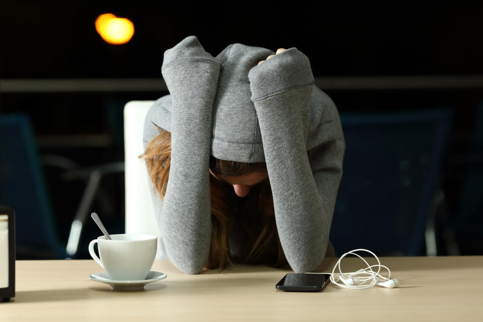 Front view portrait of a sad teenager complaining in a bar in the night