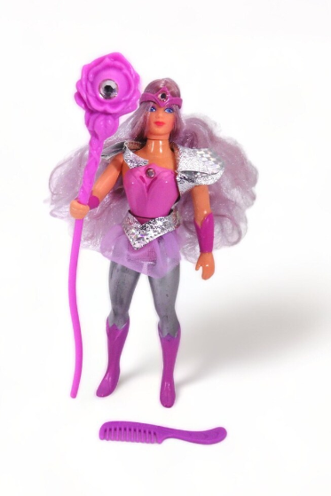 Vintage She-Ra action figure with cape, tiara, shield, and sword, alongside a comb