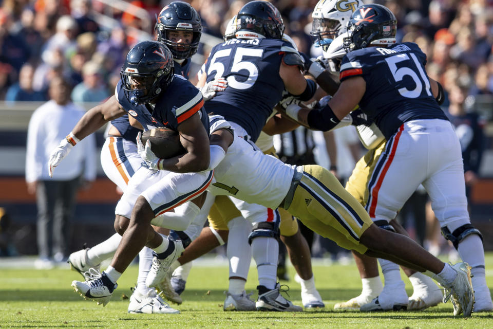 Virginia running back Mike Hollins, left, is tackled by Georgia Tech defensive back LaMiles Brooks (1) during the first half of an NCAA college football game Saturday, Nov. 4, 2023, in Charlottesville, Va. (AP Photo/Mike Caudill)