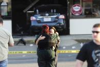 A Sunset Police officer (R), and another law enforcement officer embrace in front of the Sunset Mini Mart where a man drove his vehicle into the store in Sunset, Louisiana, August 26, 2015. A police officer was shot and two people stabbed in a southwest Louisiana town on Wednesday, with a suspect barricading himself in a convenience store, police said. (REUTERS/Leslie Westbrook/The Advocate)