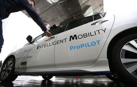 A journalist walks toward a modified Nissan Leaf, driverless car, during its first demonstration on public roads in Europe, in London, Britain February 27, 2017. REUTERS/Peter Nicholls