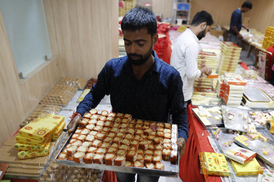 FILE - A vendor carries sweets to display for Diwali, the festival of lights, in chilbila Pratapgarh District, India, Thursday, Nov. 4, 2021. Hindus light lamps, wear new clothes, exchange sweets and gifts and pray to goddess Lakshmi during Diwali, the festival of lights. (AP Photo/Rajesh Kumar Singh, File)
