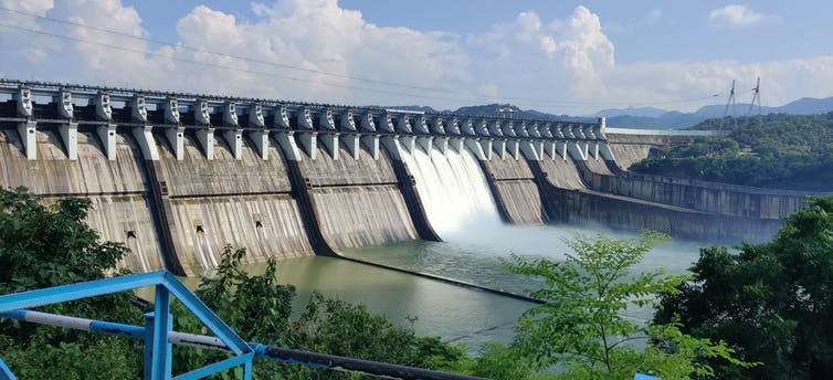 A large concrete dam surrounded by tropical forest.