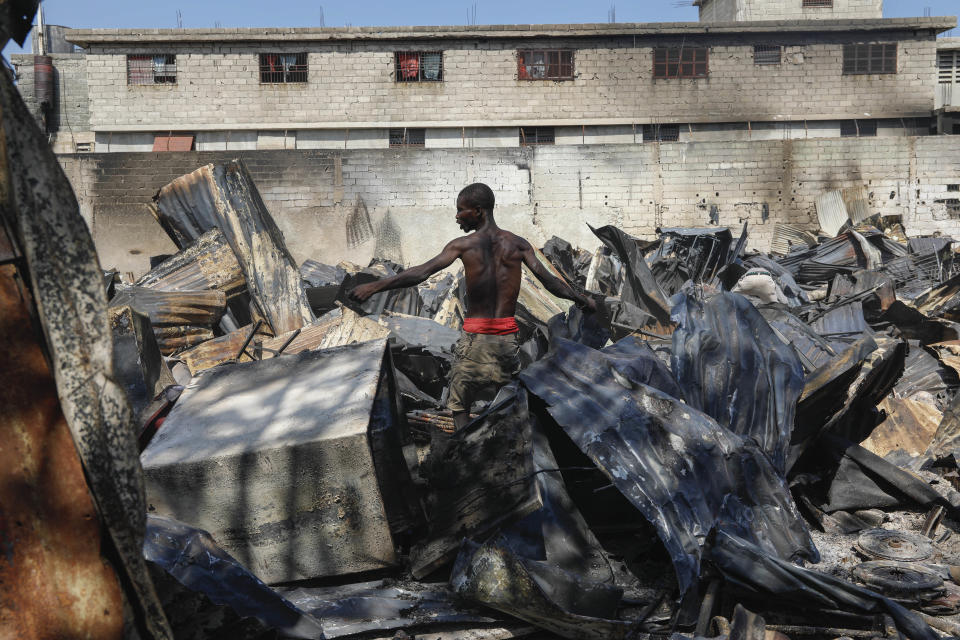 A man looks for salvageable items at a car mechanic shop that was set fire during gang violence in Port-au-Prince, Haiti, Monday, March 25, 2024. (AP Photo/Odelyn Joseph)