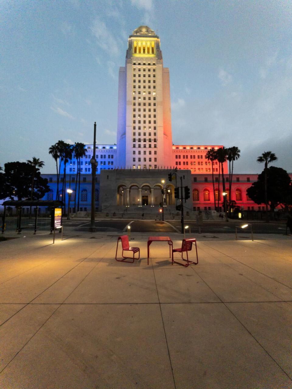 L.A. City Hall is bathed in colored lights as seen from Grand Park.