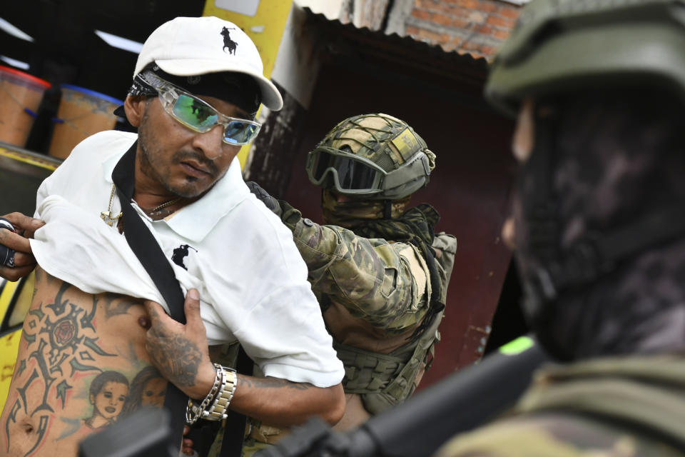 A soldier examines the back of a man checking for gang related tattoos, during a stop and frisk operation in Portoviejo, Ecuador, Thursday, Jan. 11, 2024. President Daniel Noboa decreed Monday a national state of emergency due to a crime wave tied to drug trafficking gangs. (AP Photo/Ariel Ochoa)