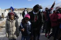 Christian Tango Mukaya, a 30-year-old asylum-seeker from Congo, right, and other migrants wave to the Pope Francis during his visit at the Karatepe refugee camp, on the northeastern Aegean island of Lesbos, Greece, Sunday, Dec. 5, 2021. Pope Francis is offering comfort migrants at a refugee camp on the Greek island of Lesbos. He is blasting what he says is the indifference and self-interest shown by Europe "that condemns to death those on the fringes." (AP Photo/Alessandra Tarantino)