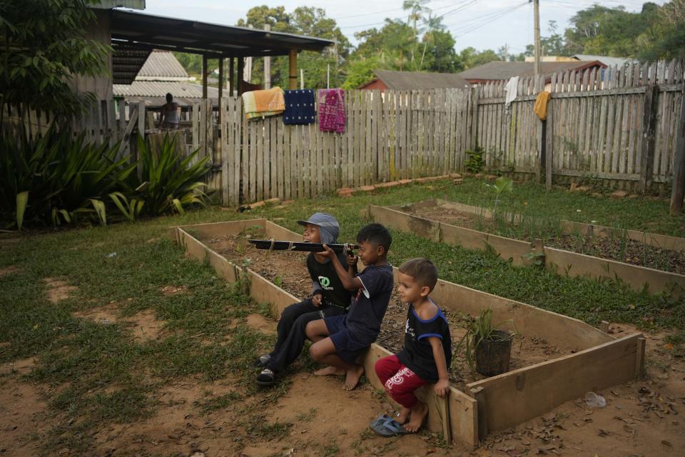 Niños venezolanos juegan con un arma de juguete, elaborada con un tubo y cuerda, en un albergue para migrantes en Assis, Brasil, el 20 de junio de 2024. La ciudad tiene poco que ofrecer a los migrantes salvo un refugio de madera y un gimnasio escolar donde pueden dormir 15 hombres. (AP Foto/Martín Mejía)