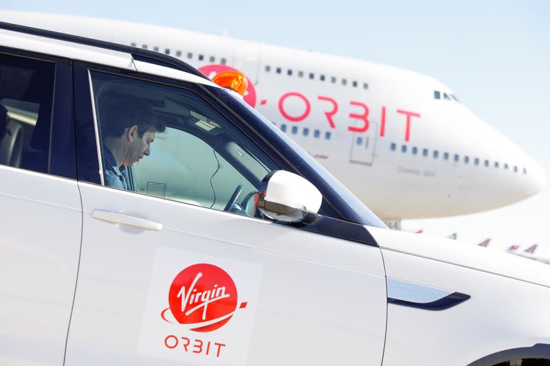 Virgin Orbit CEO Dan Hart works on email as he sits near the runway next to "Cosmic Girl", a modified Boeing 747 jetliner, prior to a drop test of its high-altitude launch system for satellites from Mojave, California