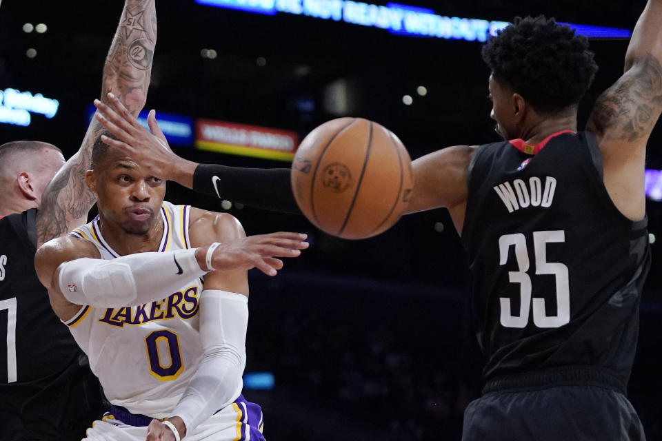 Los Angeles Lakers guard Russell Westbrook, left, passes while under pressure from Houston Rockets center Christian Wood during the first half of an NBA basketball game Sunday, Oct. 31, 2021, in Los Angeles. (AP Photo/Mark J. Terrill)