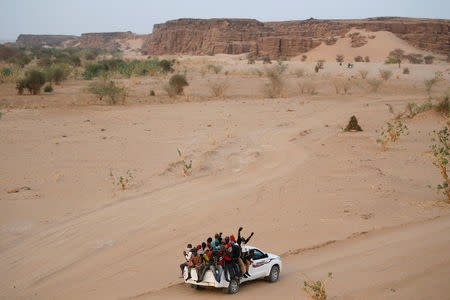 Migrants crossing the Sahara desert into Libya ride on the back of a pickup truck outside Agadez, Niger, May 9, 2016. REUTERS/Joe Penney