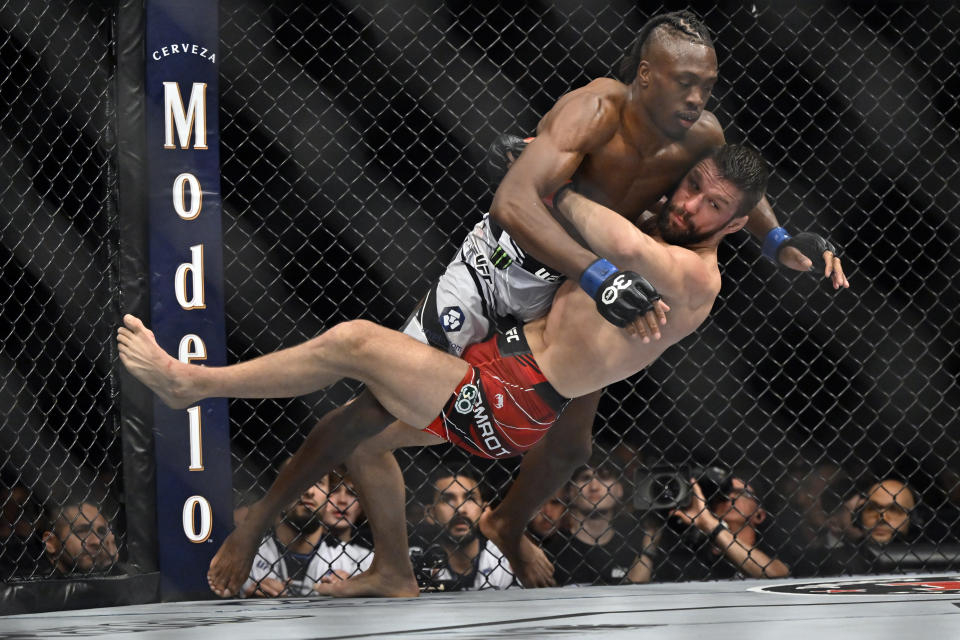 Mateusz Gamrot, bottom, pulls down Jalin Turner during a UFC 285 mixed martial arts lightweight bout Saturday, March 4, 2023, in Las Vegas. (AP Photo/David Becker)