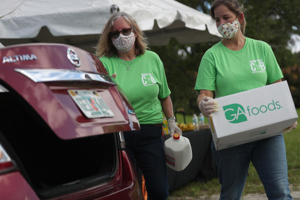 MIAMI, FLORIDA - JULY 24: Karen Sutton (L) and Maggie Izquierdo  place food in the trunk of a vehicle at a drive-thru food distribution site set up at the First Church of the Brethren on July 24, 2020 in Miami, Florida. 500 boxes of food were donated by Farm Share for those in need to help people trying to make ends meet during the pandemic. The United States economic recovery is showing signs of weakness as a renewed outbreak of COVID-19 has caused some business owners to lay employees off again, four months after the initial outbreak of coronavirus in March. (Photo by Joe Raedle/Getty Images)