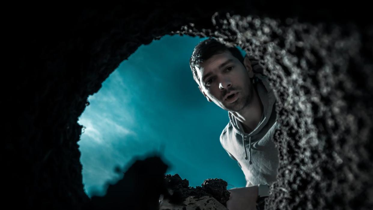 scared guy digging a deep earthen hole with a shovel during a moonlit night