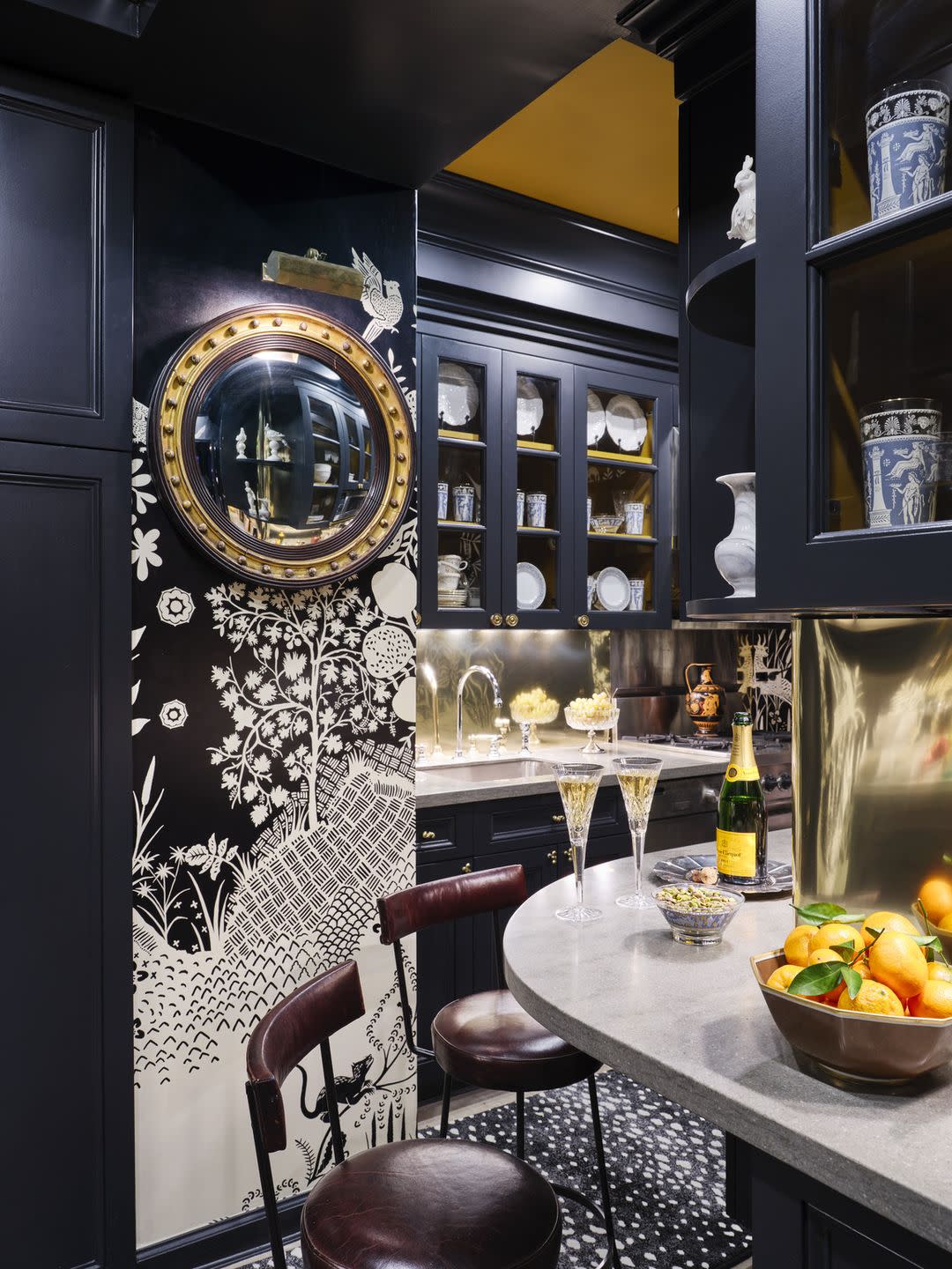 manhattan apartment of garrow kedigian in the legendary carlyle hotel a 19th century butler’s mirror offers a peek into the kitchen and its brass sheet backsplash leather stools, le forge wallpaper, christian lacroix