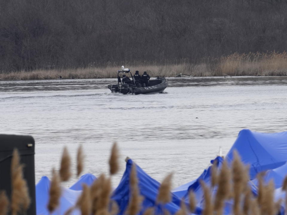 A police boat searches an area in Akwesasne, Quebec, Friday, March 31, 2023. Authorities in the Mohawk Territory of Akwesasne said Friday one child is missing after the bodies of six migrants of Indian and Romanian descent were pulled from a river that straddles the Canada-U.S. border. (Ryan Remiorz/The Canadian Press via AP)