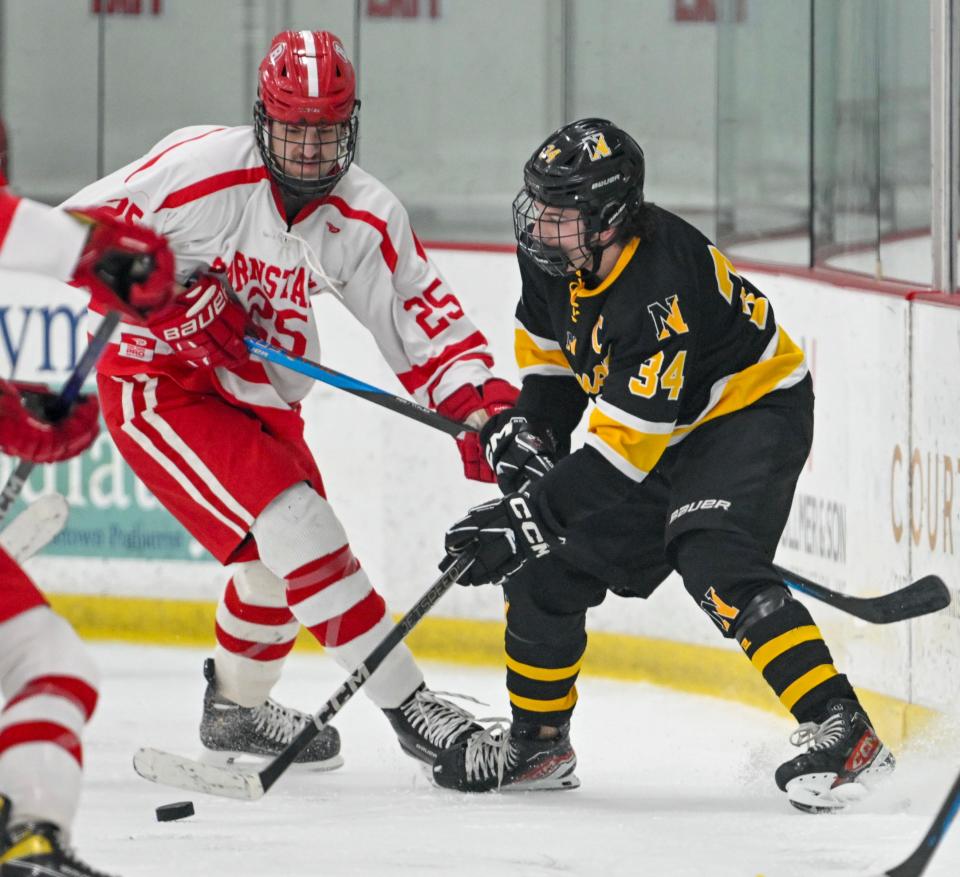 Logan Poulin of Nauset passes the puck under pressure from Chase Semprini of Barnstable boys hockey.