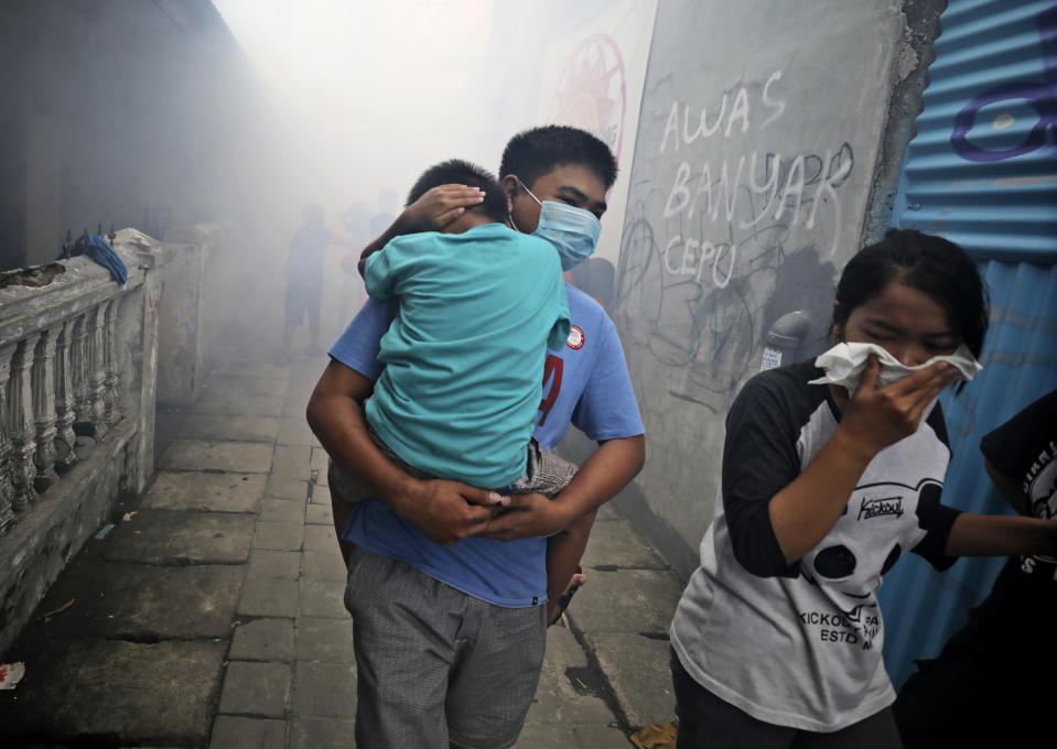 People move away as health workers fumigate a slum to prevent an outbreak of dengue fever in Jakarta, Indonesia, on Monday, March 23, 2020. While 2019 was the worst year on record for global dengue cases, experts fear an even bigger surge is possible because their efforts to combat it were hampered by restrictions imposed in the coronavirus pandemic. (AP Photo/Dita Alangkara)