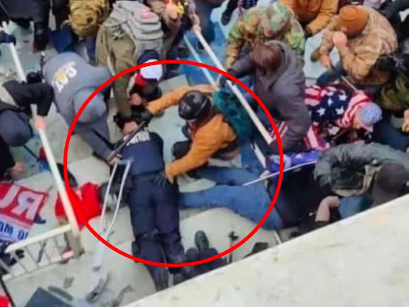 Jeffrey Sabol holds a police baton and his hand on a Capitol police officer who had been dragged down a set of stairs during the insurrection at the US Capitol. He has been arrested and is facing five years in prison. (FBI)